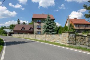 una carretera frente a una casa con una pared de piedra en Zagroda na zakręcie en Lipnica Mała