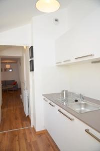 a white kitchen with a sink and a living room at Le Clos des Salins in Toulouse