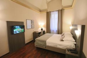 - une chambre avec un lit et une télévision dans l'établissement Hotel Boutique Antiche Mura, à Saluces