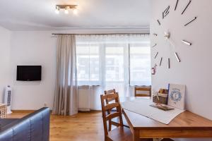 a dining room with a table and a clock on the wall at Apartamenty Lea in Kraków
