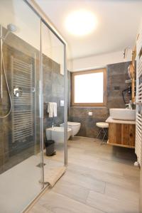 a bathroom with a toilet, tub, sink and shower stall at Wellness Hotel Dolomia in Soraga