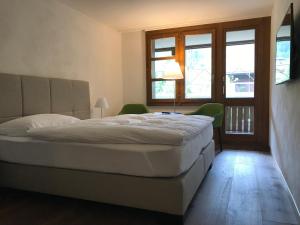 Schlafzimmer mit einem Bett, einem Tisch und Fenstern in der Unterkunft Hotel Krone Lenk in Lenk im Simmental