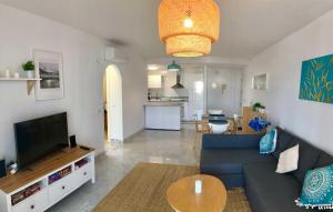 sala de estar con sofá azul y TV en Bright apartment 300m from the beach en Sitio de Calahonda