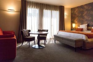 サン・マロにあるHôtel L'Adresseのベッド、テーブル、椅子が備わるホテルルームです。