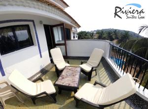 a patio with white chairs and a table on a balcony at Susegad Suites Arpora Apartments & Villas with Reserved Parking in Arpora