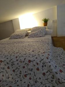 sypialnia z łóżkiem z kwiatową narzutą i poduszkami w obiekcie Estudio "La Cochera de Sorrapa" w mieście Deltebre