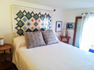 um quarto com uma cama branca com almofadas em Ca n'Antonia Formentera em Sant Francesc Xavier