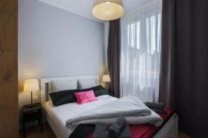 グダニスクにあるCentral Apartments Rajskaのベッドルーム1室(ピンクの枕が付いたベッド1台付)