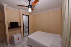 a bedroom with a bed and a ceiling fan at Hotel Castanheira in Ipatinga