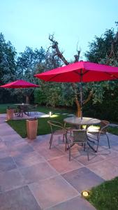 un patio con mesas y sillas y sombrillas rojas en Il carpino bianco, en Puegnago sul Garda