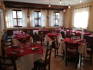 una sala da pranzo con tavoli e sedie rossi e finestre di CHALET SEGGIOVIA a Pontechianale