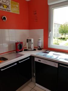a small kitchen with red walls and a window at fecamp in Fécamp