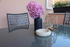 um vaso com flores cor-de-rosa numa mesa com duas cadeiras em Studio apartment Laura || em Murter