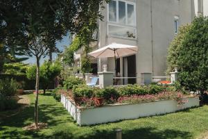 a house with an umbrella and flowers in a yard at Apartments Lucija in Zadar