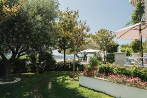 a garden with an umbrella and the beach in the background at Apartments Lucija in Zadar