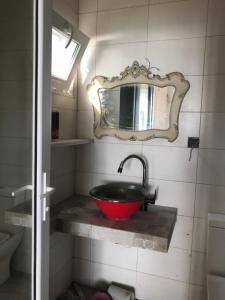 baño con lavabo rojo y espejo en Mana-Mana, en Grigoleti