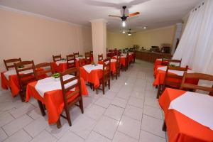 ein Esszimmer mit Tischen, Stühlen und orangefarbenen Tischen in der Unterkunft Hotel Castanheira in Ipatinga