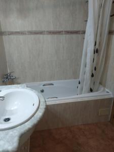 ein Badezimmer mit einem Waschbecken und einer Badewanne mit einem Duschvorhang in der Unterkunft Cal Músic in Antella