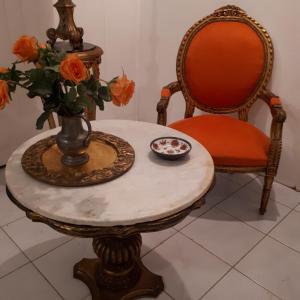 a table with a vase of orange roses and a vase at TERRASSE DU PITON in Deshaies