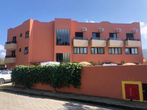 um edifício laranja com uma sebe à frente dele em Hotel Ponta das Toninhas em Ubatuba