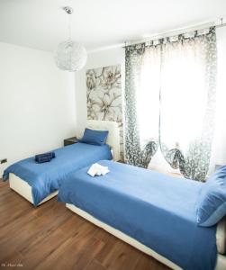 2 camas en un dormitorio con sábanas azules y ventana en Casa Bologna Fiera, en Bolonia