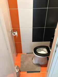 a bathroom with a toilet with a black and orange floor at Palace - Belvárosi Apartman Eger in Eger