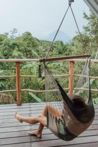 a woman sitting in a hammock on a deck at Selvista Guesthouses in Balgue