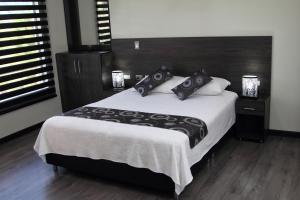 ein Schlafzimmer mit einem großen Bett mit schwarzen und weißen Kissen in der Unterkunft TL Casa Blanca Hotel Boutique Sibundoy Putumayo in Sibundoy