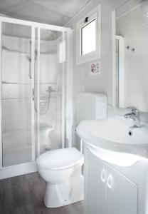 a white bathroom with a toilet and a sink at Camping Genova Est in Bogliasco
