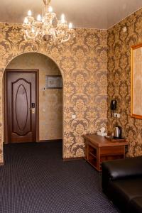 Habitación con lámpara de araña, puerta y mesa. en Malibu Hotel, en Omsk