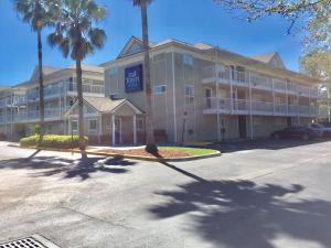 a large building with palm trees in front of it at InTown Suites Extended Stay Jacksonville FL St Johns Bluff Rd in Jacksonville