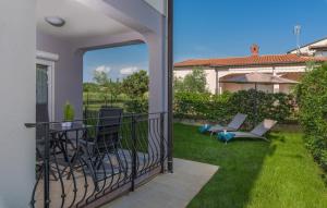 a balcony with chairs and an umbrella on the grass at Silver Holiday House in Poreč