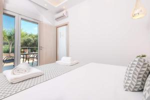 a white bedroom with a bed and a balcony at Polyxeni's Studios in Limenas