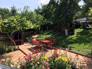 una mesa de picnic y bancos en un jardín con flores en Pensiunea Alina, en Agapia