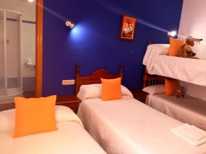 um quarto com três camas e uma parede azul em Hostal Restaurante Ego's em Campo de Criptana