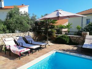 a patio with chairs and an umbrella next to a pool at Casa Emma in Krk
