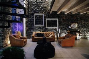 un soggiorno con divani in pelle e un muro in pietra di Ghè House a Catania
