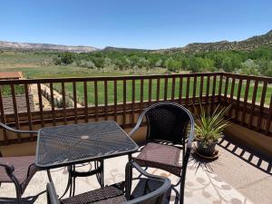 Un patio con dos sillas y una mesa en un balcón. en Slot Canyons Inn Bed & Breakfast, en Escalante