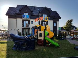 un parque infantil en el césped frente a una casa en RESORT Riva & Avir, en Jastrzębia Góra