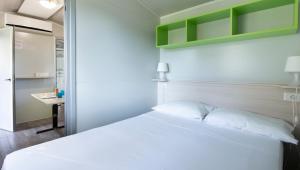 1 dormitorio con cama blanca y escritorio en Camping Genova Est, en Bogliasco