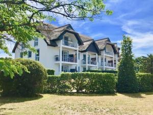 ein großes weißes Haus mit Büschen davor in der Unterkunft Ferienwohnung Seeblick - Insel Usedom in Balm