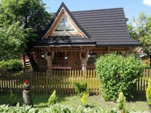una pequeña casa de madera con una valla de madera en Domek Góralski W Ogrodzie, en Małe Ciche