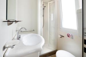 a white bathroom with a sink and a shower at Camping Genova Est in Bogliasco