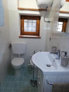Baño blanco con aseo y lavamanos en La Casa Rosa en Porto Santo Stefano