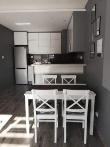 uma cozinha com uma mesa branca e 2 cadeiras em Golden Mazury Apartament em Giżycko