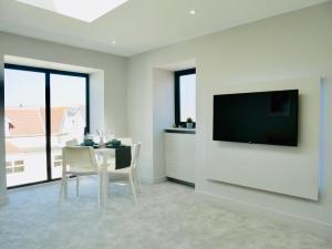 a dining room with a table and a television on a wall at Stunning Sea View Apartment Near the Beach, Bournemouth & Poole in Bournemouth