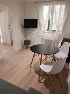 uma sala de estar com uma mesa e cadeiras e uma televisão em Appartement 1 - tout équipé et fonctionnel - Carmes, Toulouse em Toulouse