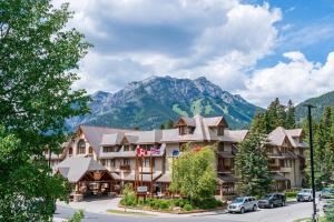 a large building with a mountain range and trees at Banff Caribou Lodge and Spa in Banff