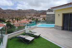 une terrasse avec deux chaises longues et une piscine dans l'établissement Villa Sunset Tauro, à Mogán