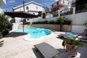 - une piscine avec 2 chaises et un parasol dans l'établissement Apartments Sakal, à Trogir